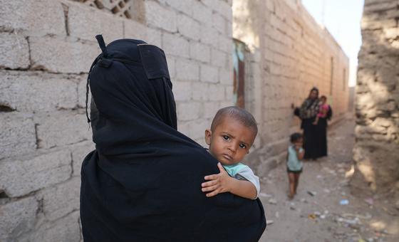 一名幼童被母亲抱着穿过也门拉赫省哈瓦塔镇的街区。